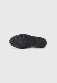 Semelle de chaussure en caoutchouc noir avec des crampons profonds et des motifs multidirectionnels pour l'adhérence. Pointe arrondie et talon renforcé pour plus de durabilité.
