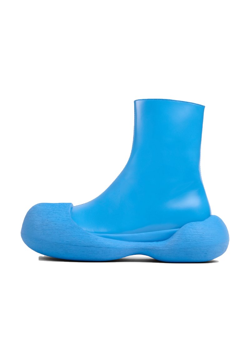 Botín de piel azul hasta el tobillo con una suela texturada y redondeada, que presenta una parte superior suave y una área de punta pronunciada y bulbosa.