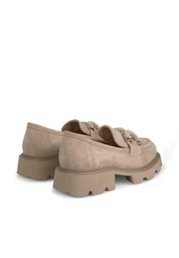 Scarpe in suede beige con punta arrotondata, linguetta ampia e dettagli in argento su una suola spessa e texturizzata. La vista posteriore mostra un profilo basso.