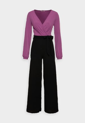 Haut violet à manches longues enroulé associé à un pantalon large noir, avec une taille nouée et une texture de tissu lisse.