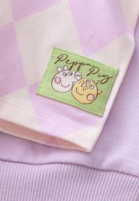 Roza in sivkasto modra tkanina s črtami, okrašena s prišito zeleno značko »Peppa Pig« z risanimi živalskimi motivi. Mehka bombažna tkanina z teksturiranimi poudarki.