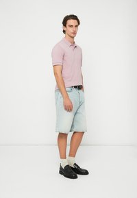 Gaiši violets polo krekls, džinsa šorti, melni apavi un baltas zeķes. Ikdienas apģērbs ar pieguļošu dizainu un kontrastējošām krāsām.