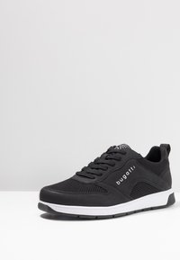 Black athletic shoe with mesh and synthetic material, featuring a white sole and logo, rounded toe, and traditional lace-up design.