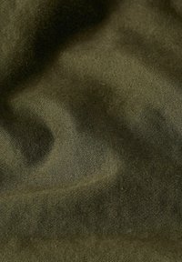 Tessuto verde oliva con una superficie liscia, caratterizzato da sottili righe diagonali e una leggera lucentezza. Il materiale si drappeggia, creando morbidi pieghe.