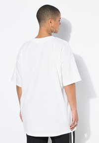 Wit oversized T-shirt met korte mouwen en een ronde hals. De stof lijkt zacht en glad, met een ontspannen pasvorm en een rechte zoom.