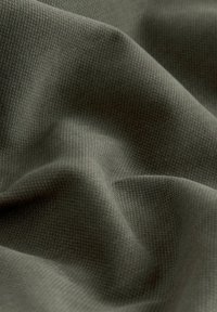 Close-up of wrinkled, textured fabric in muted olive green with subtle shadows highlighting its soft, woven surface.