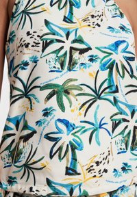 Tejido con estampado floral que presenta palmeras en tonos de azul, verde y amarillo sobre un fondo crema; textura suave con un ligero brillo.