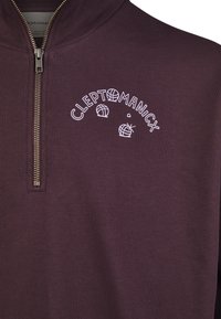 Bordeauxfarbener Reißverschluss-Hoodie mit hohem Kragen, der über weiße "CLEPTOMANICX"-Bestickung und Motivdetails verfügt. Glatte Textur, metallischer Reißverschluss.