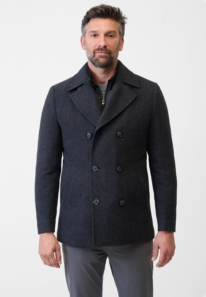 Donkergrijze wolmix peacoat met dubbele knopen, geknipte kraag en zijzakken. Draagt over een zwart ritsjack.