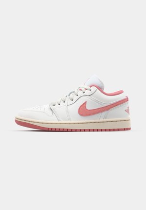 Niske bijele tenisice s ružičastim naglasima, s kožnom gornjom površinom, perforiranim prstima, okruglim vezicama i bež gumiranim potplatom. Nike logo s strane.