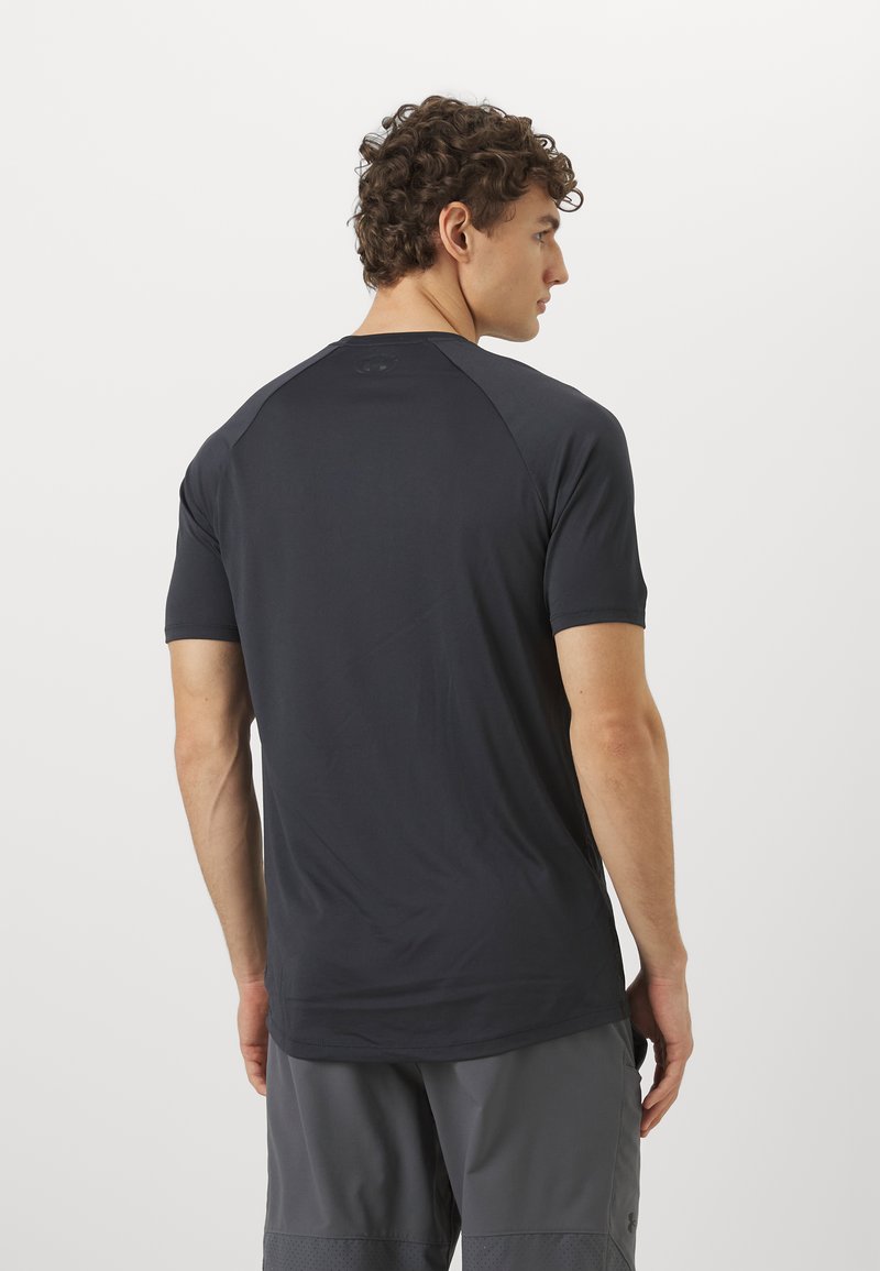 Camisa deportiva de manga corta en gris oscuro, con una textura suave, mangas raglán y un pequeño logo en la parte posterior. Adecuada para ropa deportiva.