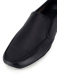 Czarny skórzany but wsuwany z okrągłym noskiem, subtelnymi przeszyciami i kontrastującą białą gumową podeszwą. Gładka faktura bez widocznych wzorów.