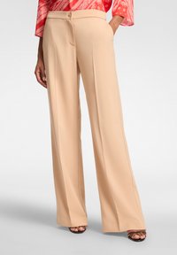 Pantaloni beige a gamba larga realizzati in un tessuto liscio e leggero, con chiusura frontale a bottone e pieghe sottili per un tocco di dettaglio in più.