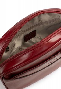 Borsa in pelle rossa con una texture liscia, una tasca con zip e una fodera in raso con dettagli brandizzati. Include una tasca interna con zip.
