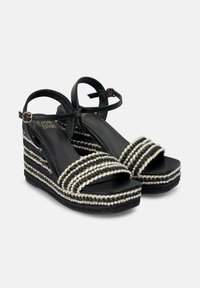 Zwarte wedge-sandalen met geweven touwdetails, voorzien van zilveren kralen en een platformontwerp. Verstelbare enkelband voor een veilige pasvorm.