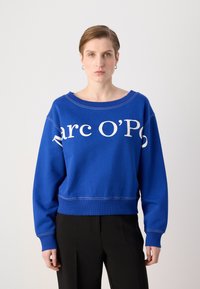 Zila džemperis ar baltu "Marc O’P" tekstu, apaļa kakla izgriezums, ribotie piedurkņu un apakšmalas gali, izgatavots no mīksta auduma, nedaudz īsāks dizains.