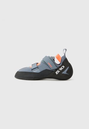 Chausson d'escalade avec un dessus en synthétique gris, une semelle en caoutchouc noir et des accents orange. Inclut des sangles velcro doubles et un talon renforcé.