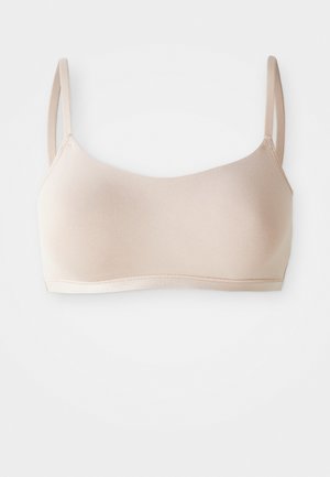 Seamless light beige soft fabric bra with thin adjustable shoulder straps and elastic underband on white background.