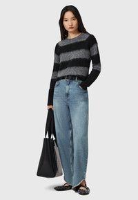 Maglione a righe nere e grigie, jeans azzurri larghi con orlo sfrangiato, borsa a tracolla nera e ballerine nere con borchie. Design semplice e casual.
