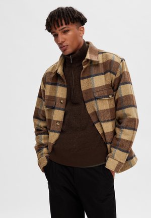 Brown plaid wool jacket with two chest pockets, tan and blue accents, button closure, and a textured collar. Worn over a brown sweater.