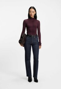 Långärmad, ribbad, vinröd topp som matchas med mörkblå raka jeans. Svarta klackade ankelstövlar och en strukturerad handväska. Enkel design.