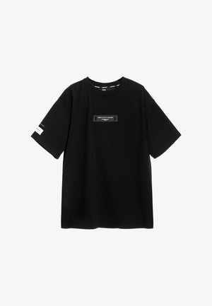 Camiseta de algodón negra con mangas cortas, corte oversize, cuello redondo y un parche rectangular central con logo. Presenta rayas de acento blancas en las mangas.