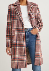 Abrigo de cuadros en tejido suave que presenta tonos de rosa, azul y crema, con un cuello estructurado, dos bolsillos delanteros y un corte relajado.