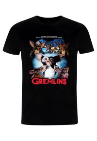Černé tričko s centrálním grafickým motivem zobrazujícím bílé a šedé stvoření obklopené Gremliny. Pod obrázkem je text "Gremlins" v červené barvě.