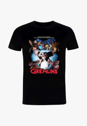 T-shirt noir arborant un graphique central d'une créature blanche et grise entourée de Gremlins. Le texte « Gremlins » est inscrit en rouge sous l'image.
