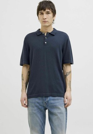 Navy polo shirt with a knitted texture, short sleeves, two-button placket, and a relaxed fit, paired with light blue jeans.