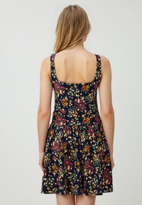 Abito floreale con sfondo blu navy, caratterizzato da un corpetto aderente e una gonna svasata. Il materiale sembra leggero; presenta vivaci motivi di fiori multicolori.