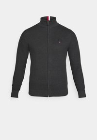Maglione grigio scuro con zip, con un motivo a maglia testurizzato, un colletto alto e dettagli a strisce rosse e bianche in contrasto all'interno del colletto.
