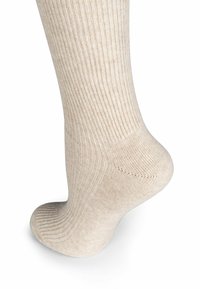 Calze lavorate a maglia di colore beige chiaro con una texture a coste. Lunghezza alla caviglia, dotate di punta liscia e tallone rinforzato per una maggiore durata.