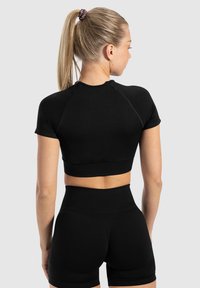 Zwarte fitted crop top met korte mouwen en een brede zoom, gecombineerd met zwarte high-waisted shorts met een gladde, rekbare textuur.