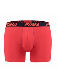 Red boxer shorts made from cotton, featuring a navy elastic waistband with orange "PUMA" logo, smooth texture, and fitted design.