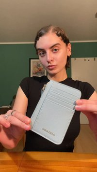 Light blue cardholder with four slots, zip closure, textured material, branded with "ANNA FIELD" in gold foil at the bottom edge.