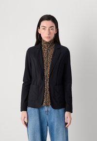 Schwarze weiche Blazerjacke mit zwei Fronttaschen, kombiniert mit einem braunen Leopardenmuster-Hochauskragen-Zip-Top und lockeren blauen Denim-Jeans.