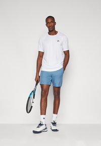 Valge sportlik t-särk, helesinised lühikesed püksid, valged tossud tumesiniste detailidega ning tennisereket. Sportlik disain, mugav lõige.