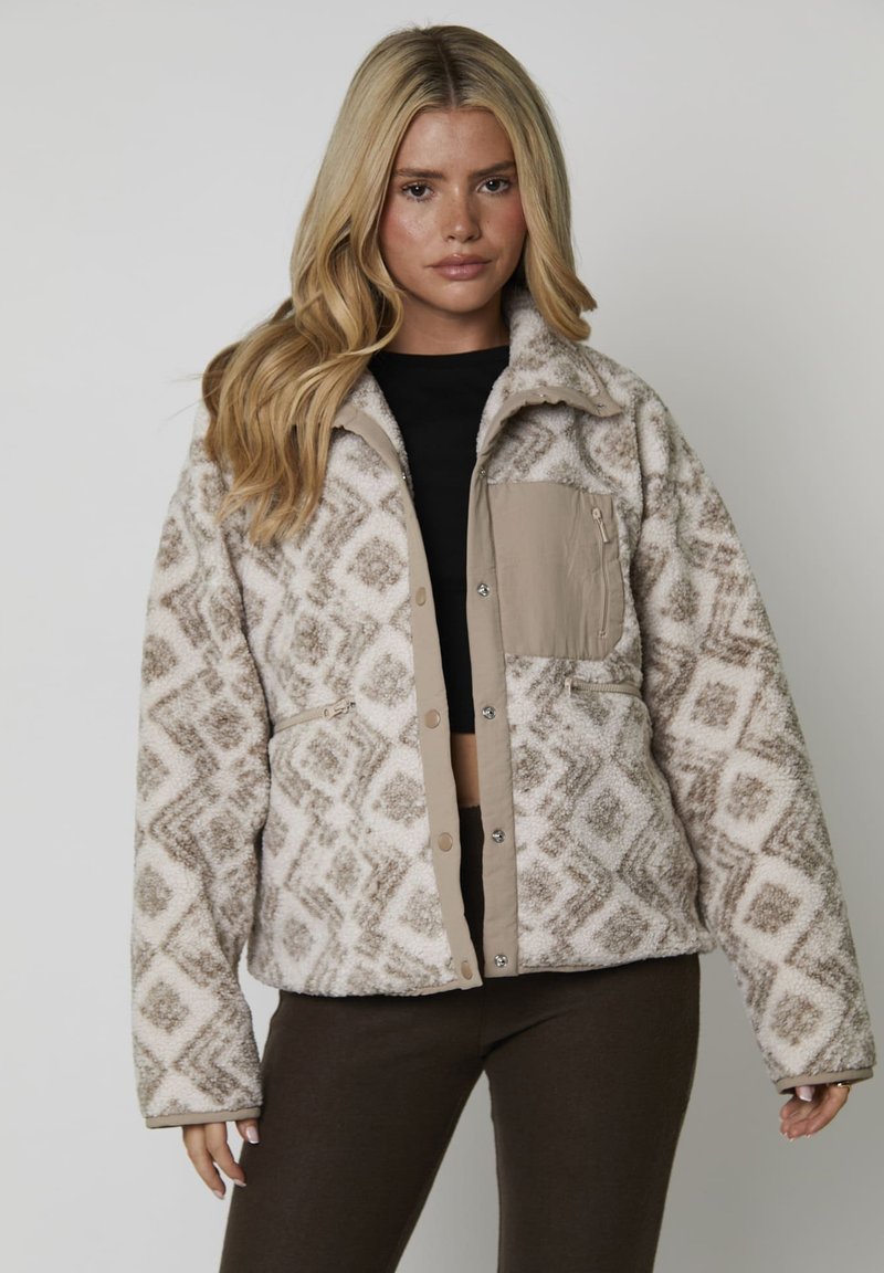 Giacca in pile con un motivo geometrico beige e bianco sporco, dotata di una tasca frontale e bottoni a pressione, tessuto testurizzato e vestibilità over.