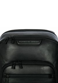 Zaino in pelle nera con due scomparti con cerniera, logo "Porsche Design" in rilievo e superficie liscia al tatto.