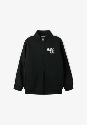 Veste noire zippée avec des bandes blanches sur les manches et un texte blanc "HAVOC" sur la poitrine en haut à gauche, poignets côtelés et poches devant.