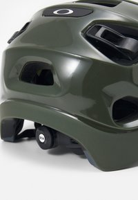 Close-up de um capacete de bicicleta verde, mostrando os furos de ventilação e um botão BOA ajustável na parte de trás.