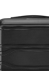 Zwarte harde koffer met een gestructureerd oppervlak met een honingraatpatroon, stevige handgreep en ritsluiting.