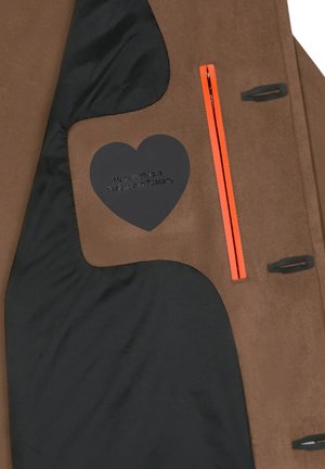 Interno di un cappotto in tessuto scamosciato marrone con una fodera nera. Presenta una cerniera arancione e un'etichetta a forma di cuore nera con testo stampato.