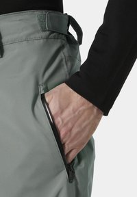 Lichtgroene, waterdichte stofbroek met een ritszak; geïntegreerde riemlussen en stofaccenten; gladde textuur en tapered pasvorm.