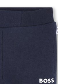 Navy blue cotton leggings with a ribbed waistband. Features a white logo on the lower right side. Smooth texture and fitted design.