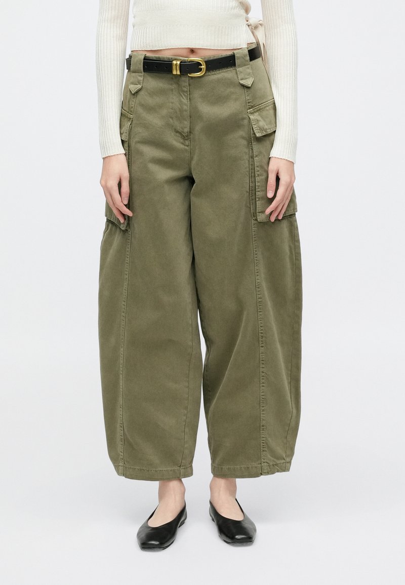 Pantaloni cargo verde măsliniu cu croială lejeră, prevăzuți cu multiple buzunare, o curea cu cataramă aurie și un material moale din bumbac.