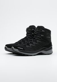 Botas de senderismo negras con parte superior de malla y gamuza, forro impermeable Gore-Tex, acentos grises y suela de goma resistente diseñada para tracción.