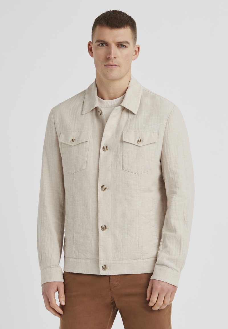Helle beigefarbene Leinenjacke mit einer Knopfleiste auf der Vorderseite, zwei Brusttaschen und einem klassischen Kragen. Sie besitzt einen strukturierten Stoff und Knopfdetails.