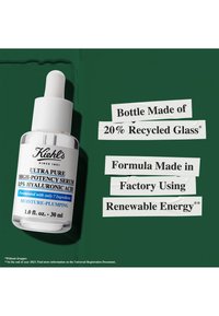 Bouteille en verre transparent avec compte-gouttes blanc, étiquetée "Sérum Ultra Pur à Haute Potence." Présente un fond vert et un texte mettant en avant des détails écologiques.